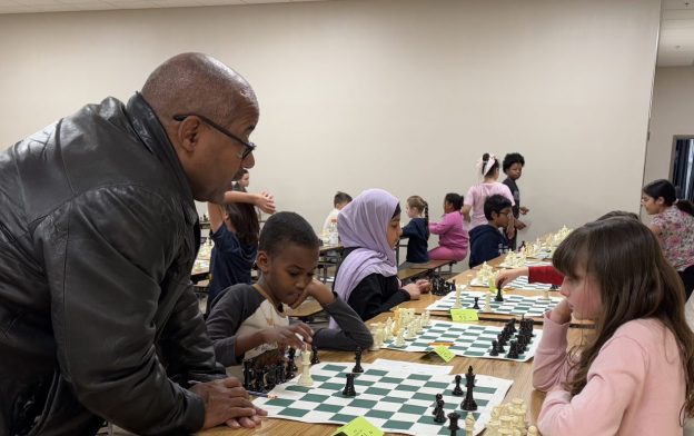 Man teaching two young children chess