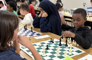 A photo of a large room full of children playing chess.